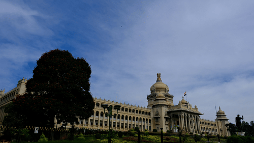 An overview of Vidhan Soudha as seen from afar with trees on the left hand side.